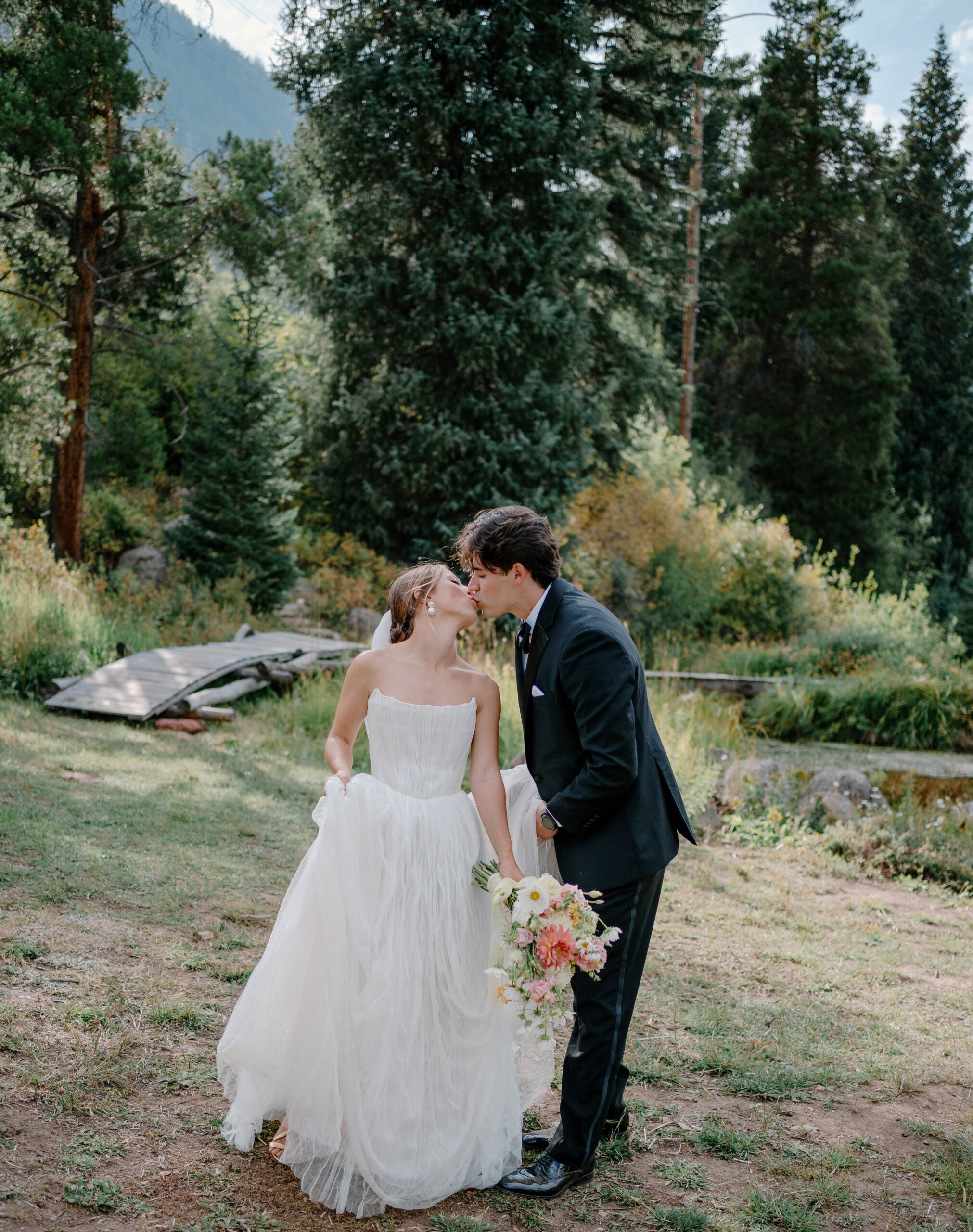 Just married couple kissing nestled in the mountains of Colorado lots of trees